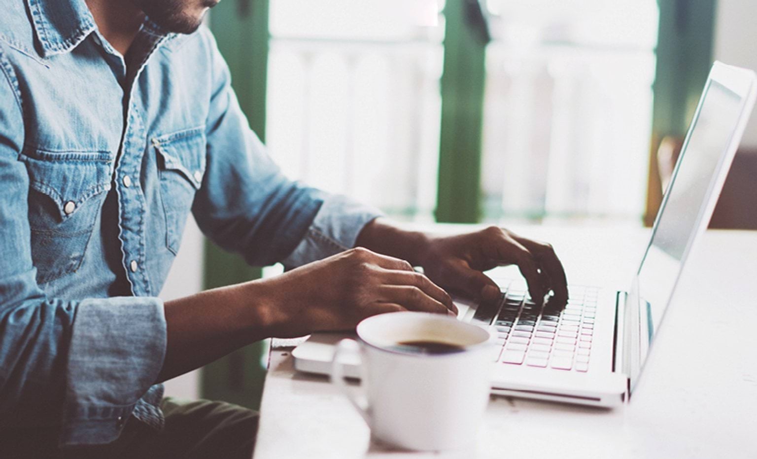 person drinking coffee while typing on computer