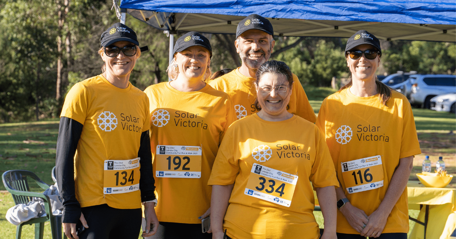 Five people in yellow t-shirts with fun run numbers pinned to their shirts
