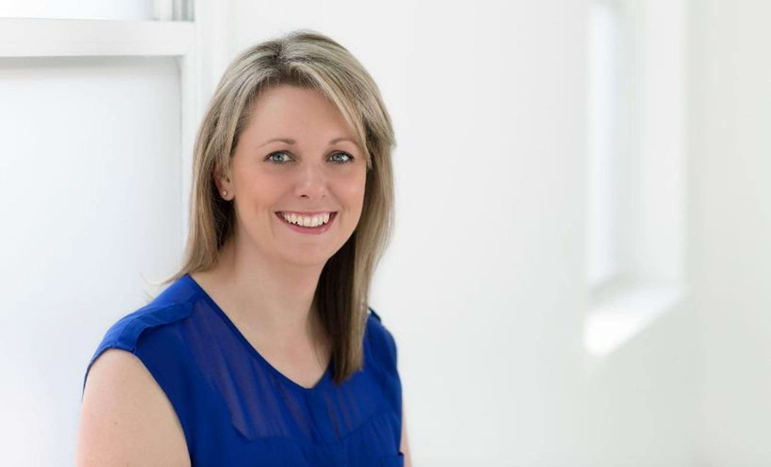 Photo of a woman in a blue top, smiling
