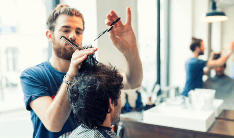 Hairdresser in a blue t-shirt cutting another person's hair