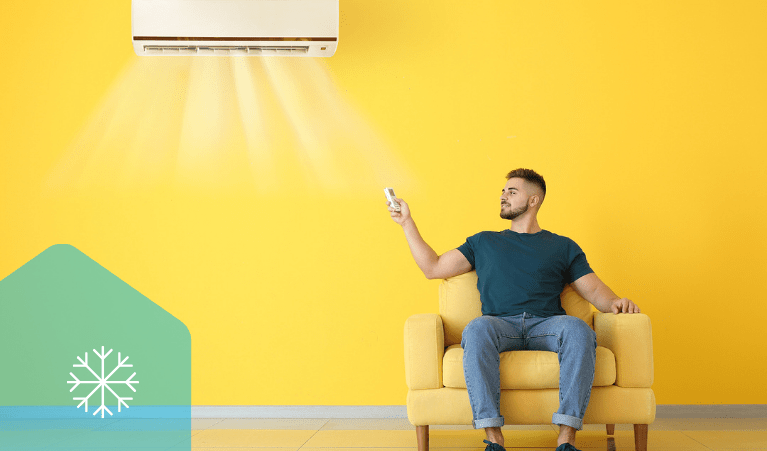 A man sitting on a yellow armchair with a yellow background, beneath a split system heater and cooler