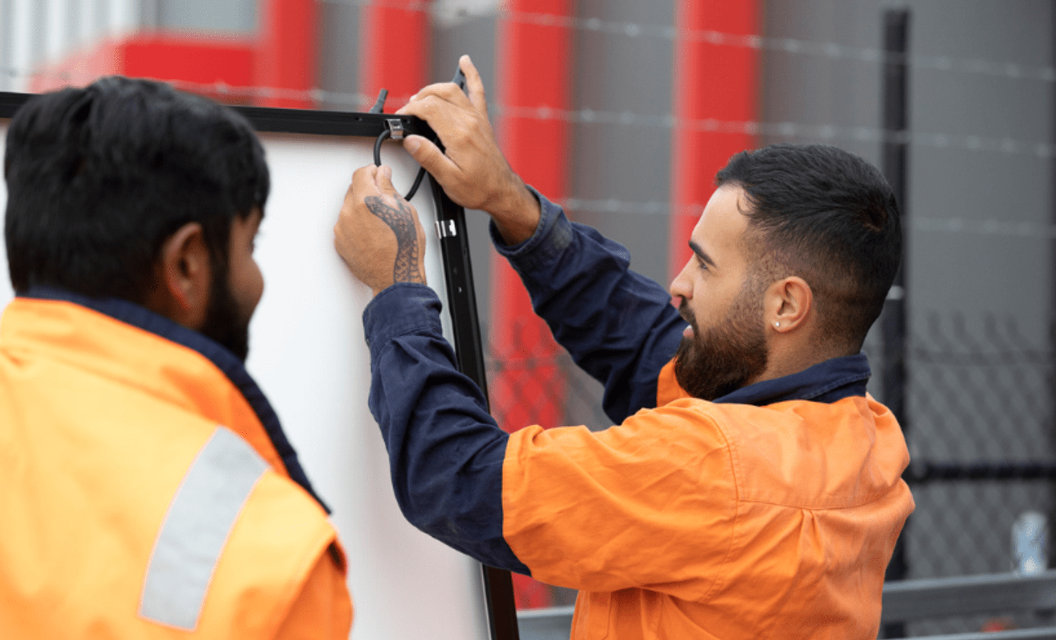two installers are working wearing orange jacket