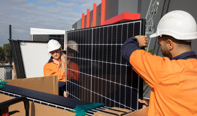 Two workers holding a solar panel.