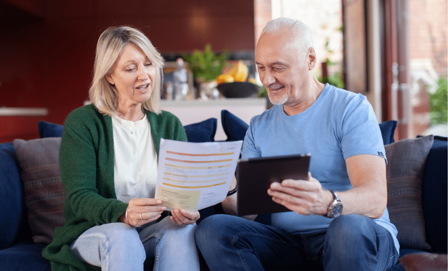 Two people reviewing a household energy bill and information on a tablet while discussing home energy costs.