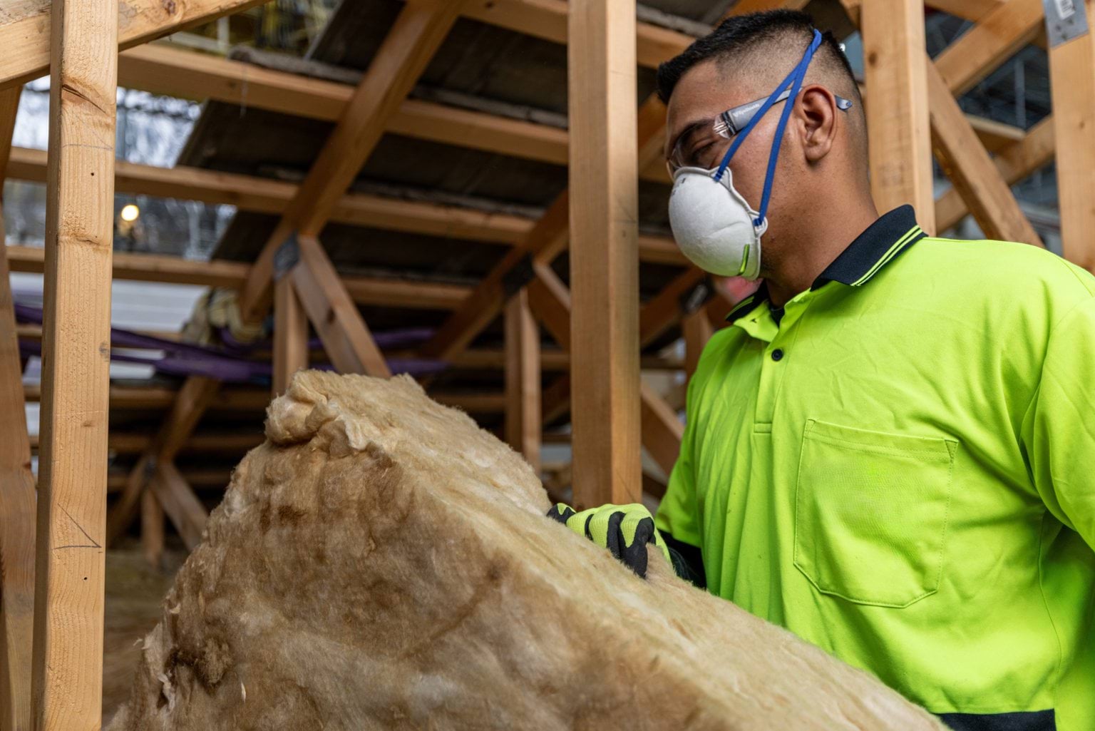 Man removing insulation from a structure wearing a safety mask and Safety glasses
